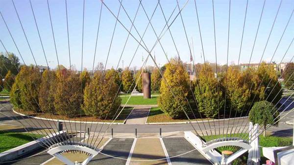 Steel cables of a white cable-stayed bridge over an autumn park