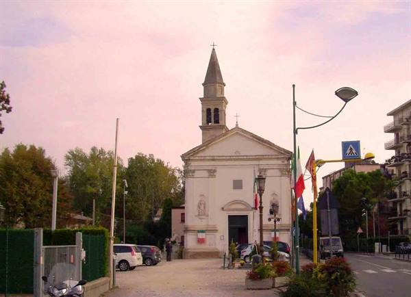 White church with bell tower among cars and flags, pink morning sky