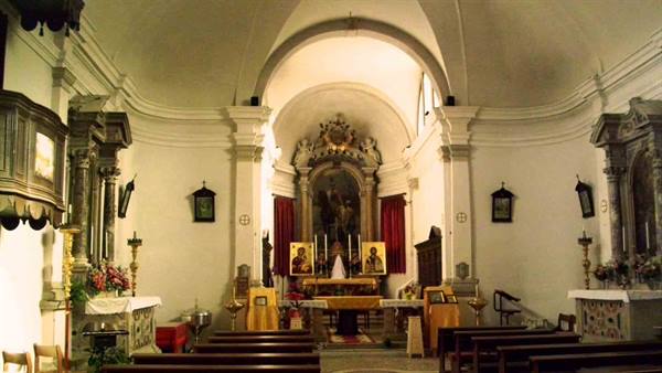 Baroque church interior with main altar, candles and wooden pews
