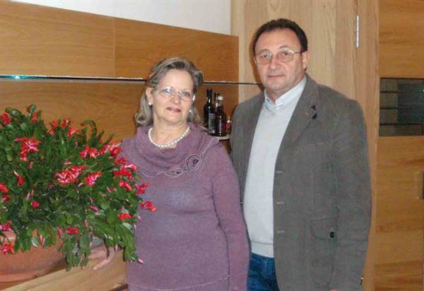 Couple indoors beside a blooming Christmas cactus in a pot