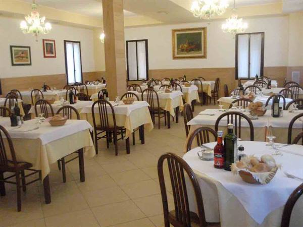Dining room with white-clothed tables set with bread and wine, lit chandeliers