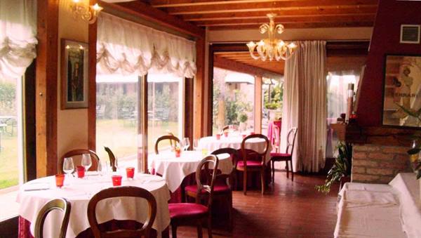 Trattoria dining room with set tables, Murano glass chandelier and windows over the garden