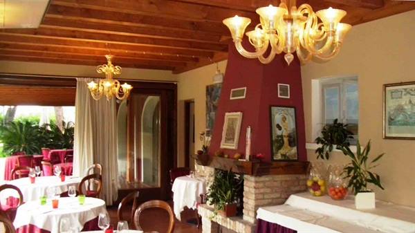 Restaurant dining room with Murano glass chandeliers, brick fireplace and set tables