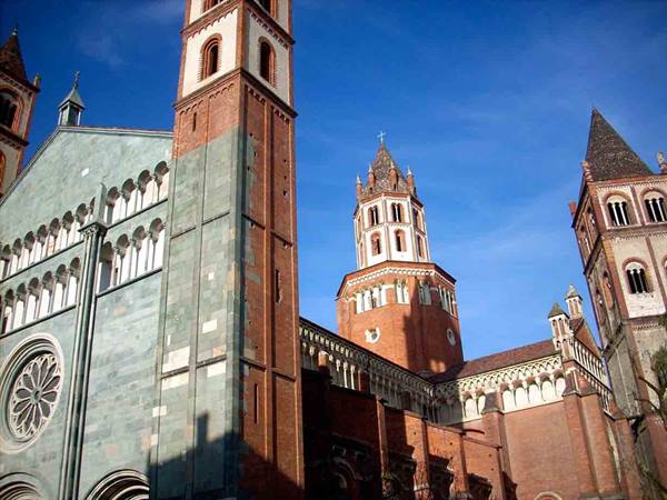 Sant'Andrea Basilica in Vercelli, brick and green stone towers under blue sky