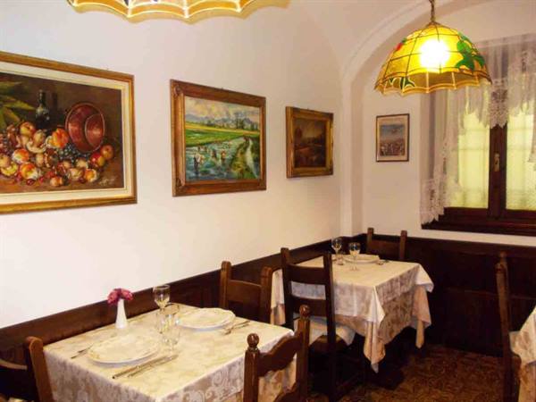 Restaurant dining room with set tables, framed paintings and yellow lamp