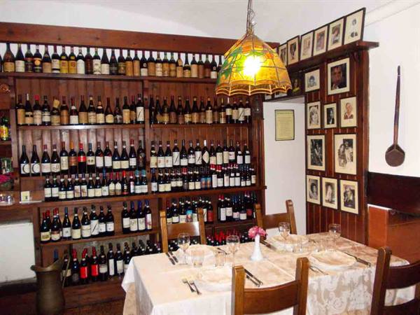 Trattoria dining room with wine bottle shelves, set table and Tiffany lamp