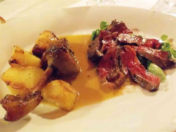 White plate with sliced rare beef and roast potatoes in gravy