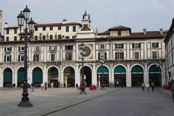 Tourists walk in Brescia's Piazza della Loggia beneath the clock tower