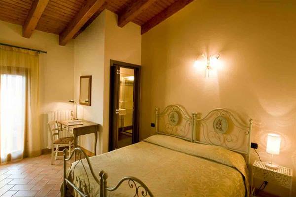 Bedroom with wrought iron bed, wooden beams and warm lighting