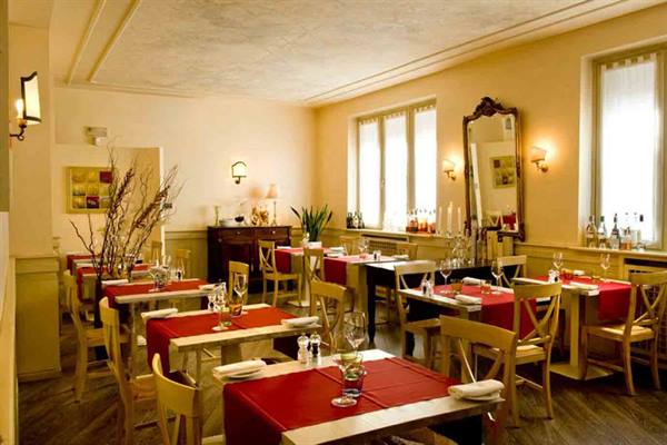 Restaurant dining room with red-tablecloth tables, wooden chairs and warm golden light