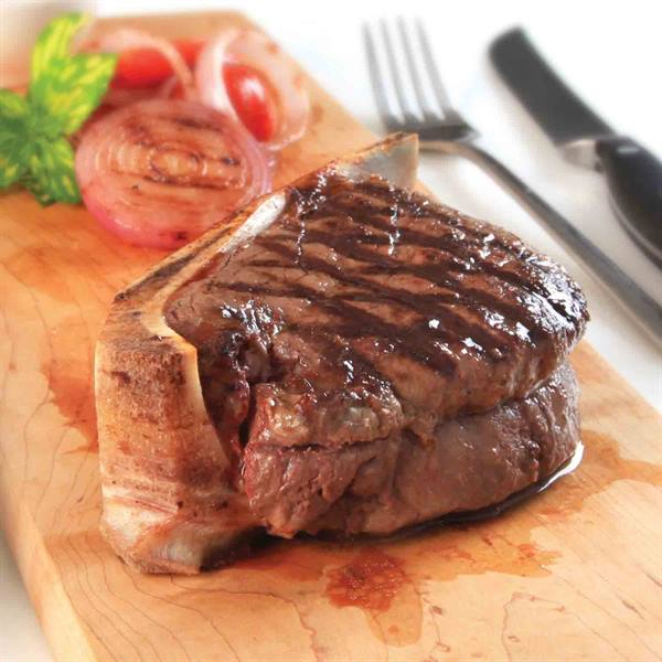 Grilled steak with red onion and cherry tomatoes on a wooden cutting board