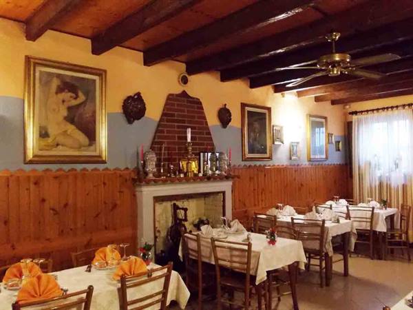 Trattoria dining room with set tables, brick fireplace and wooden beams