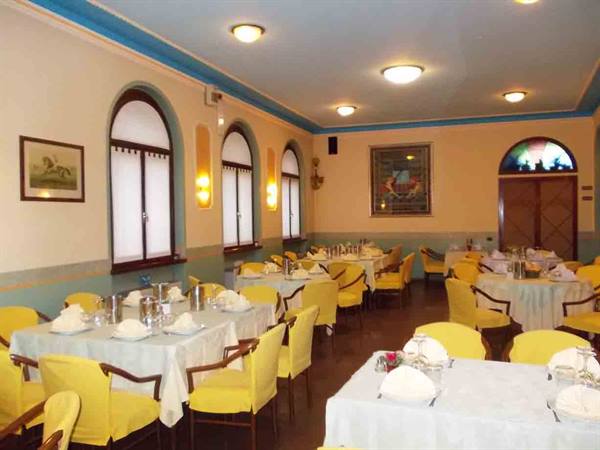 Restaurant dining room with white tablecloths and yellow chairs set for dinner