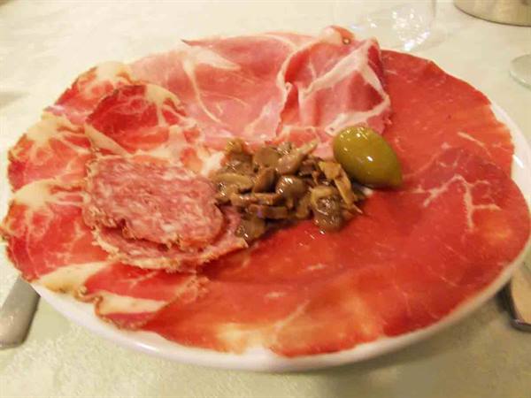 Plate of cured meats: raw ham, salami, mushrooms and an olive
