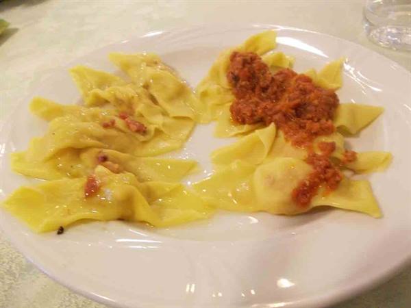 White plate with butter ravioli and meat ragù, indoor light