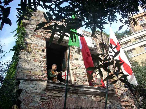 Trumpeter at the window of a medieval stone tower among flags