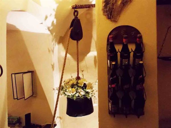 Wooden pulley with rope and white flowers, wrought iron wine rack on wall