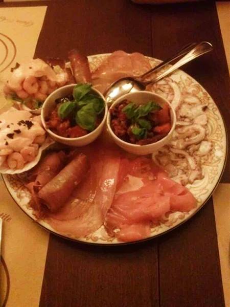 Seafood appetizer plate with salmon, shrimp, cuttlefish and two basil sauces