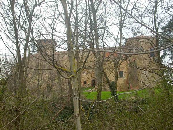 Medieval stone and brick castle behind bare trees, grey winter light