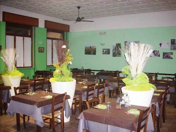 Restaurant dining room with set tables, green walls and white decorated vases