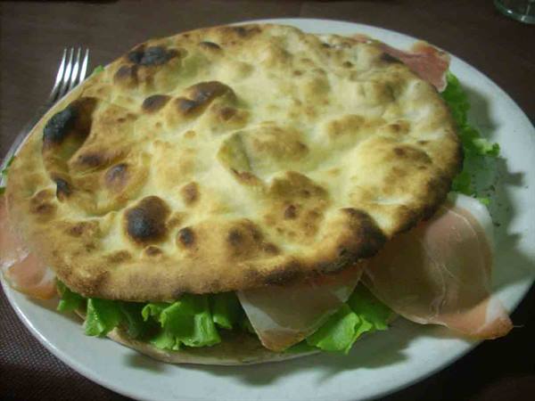 Flatbread filled with ham and lettuce on a white plate