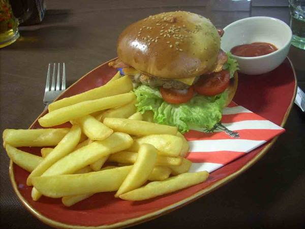 Burger with lettuce, tomato and french fries on red plate with ketchup