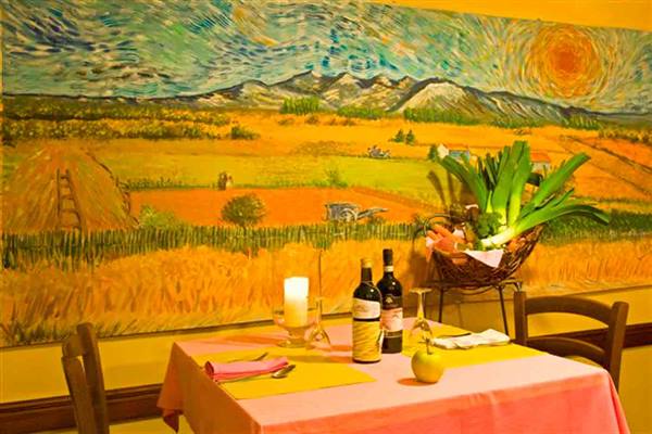 Table set with wine and candle in front of painted Van Gogh mural