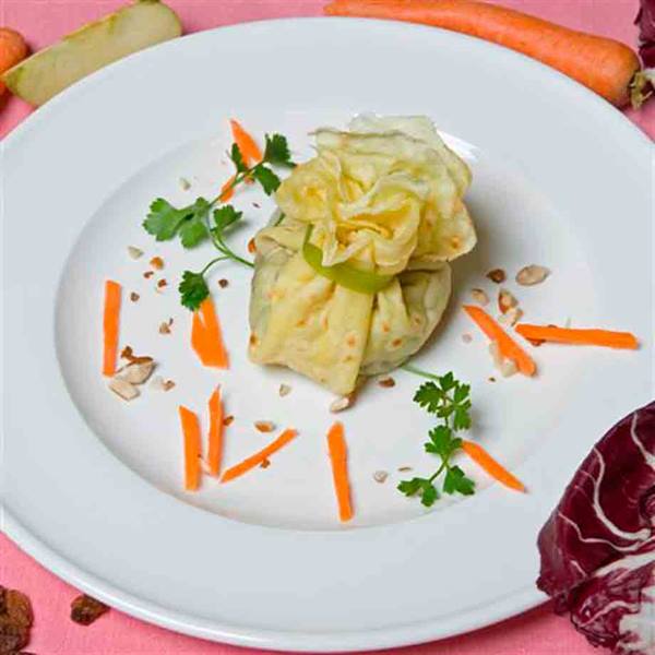 Stuffed crepe bundle on white plate with carrot sticks and parsley
