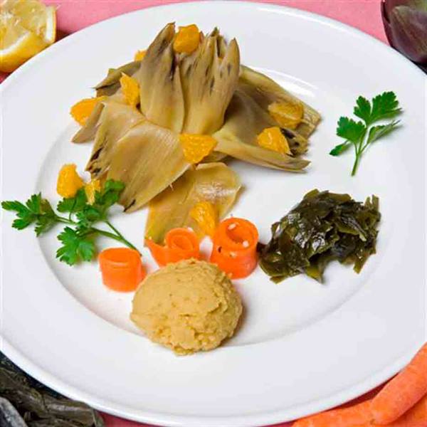White plate with artichoke, hummus, seaweed, spiral carrots and parsley