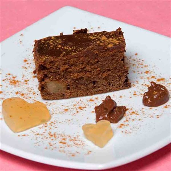 Chocolate cake on white plate with small decorative hearts and cream