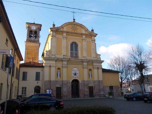 Yellow baroque church facade with bell tower, cars parked in the square