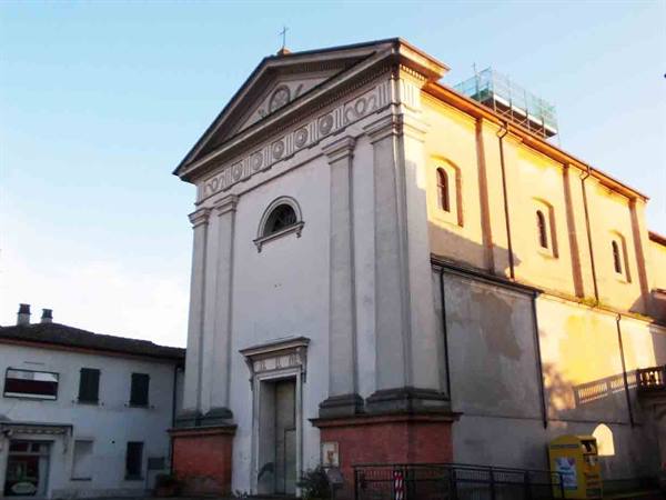 White church facade with pediment, rooftop scaffolding, warm afternoon light