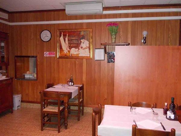 Trattoria dining room with wooden walls, set tables, painting and flowers