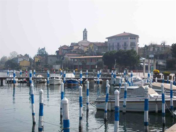 Boats moored among blue and white poles in the harbor beneath the bell tower village