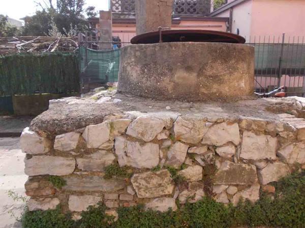 Old stone well with metal lid, dry stone wall and grass