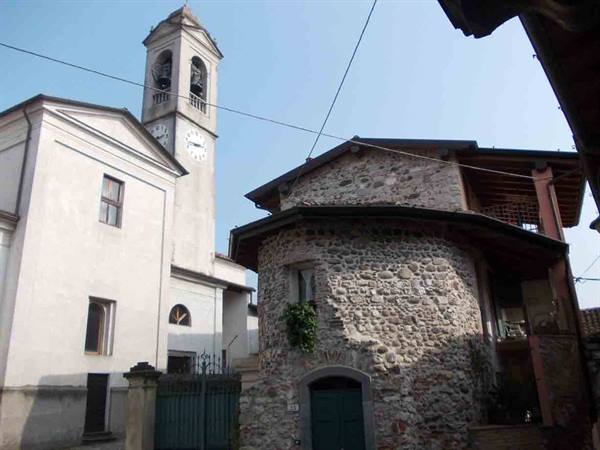 Bell tower with clock beside a stone house in daylight