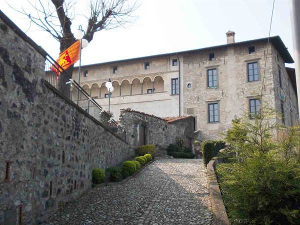Cobbled alley leading to an old stone building with arched loggia