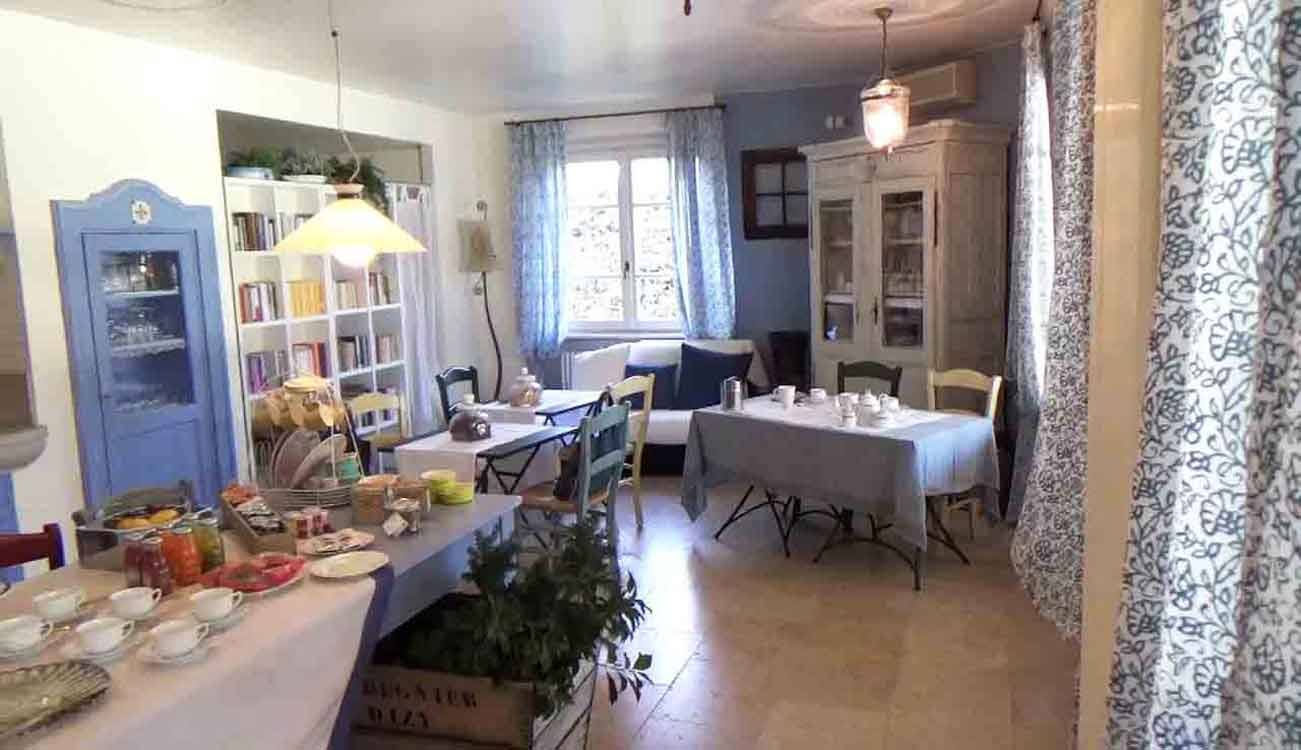 Sala colazione di un bed & breakfast: tavoli apparecchiati, libreria, armadi antichi, luce naturale