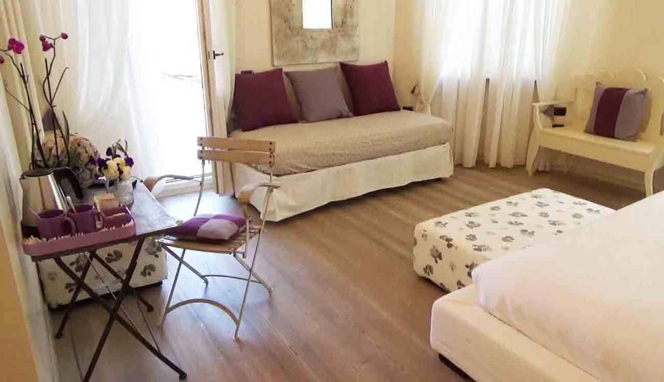 Camera da letto con divano letto, cuscini viola e vassoio con tazze