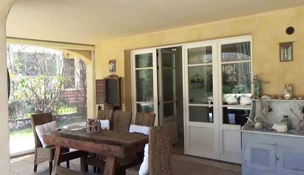 Veranda with wooden table and wicker chairs in front of open white French doors