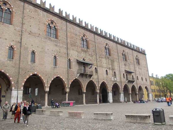 Ducal Palace in Mantua, brick facade with arcades and strolling people
