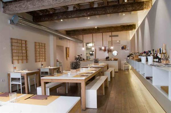 Modern trattoria dining room with wooden tables, exposed beams and bar counter