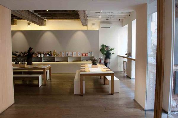 Bartender behind the lit counter, wooden tables in a minimalist interior