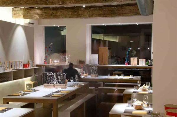 Modern restaurant dining room with wooden tables, exposed beams and waiter at work