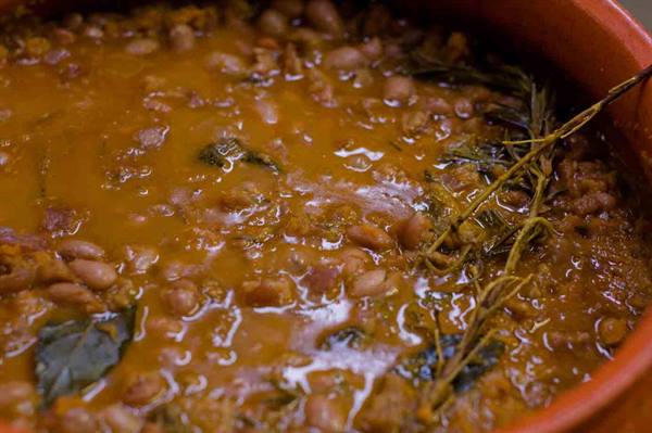 Borlotti bean soup with sage and rosemary simmering in a terracotta pot