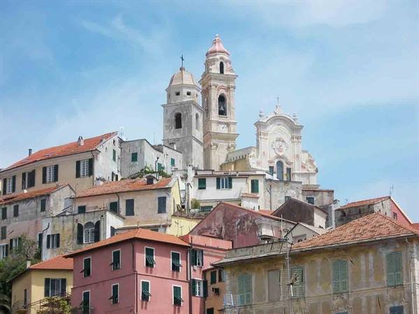Colorful houses climbing toward a baroque church with two bell towers, Cervo