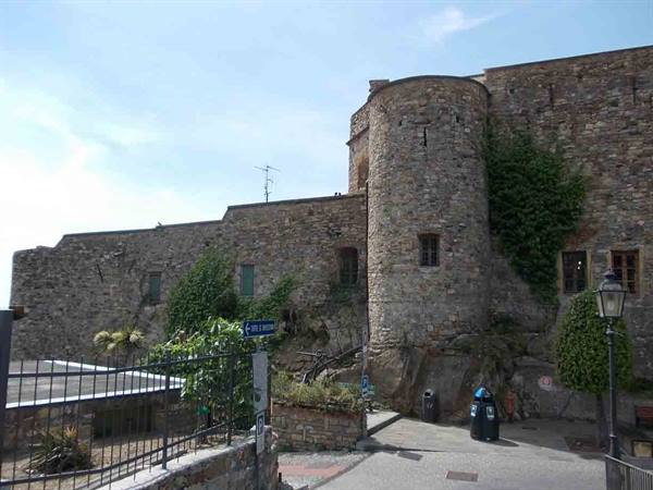 Round stone tower with ivy, ancient walls and paved street below