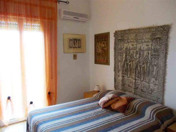 Bedroom with striped bedspread, medieval tapestry on the wall and air conditioner