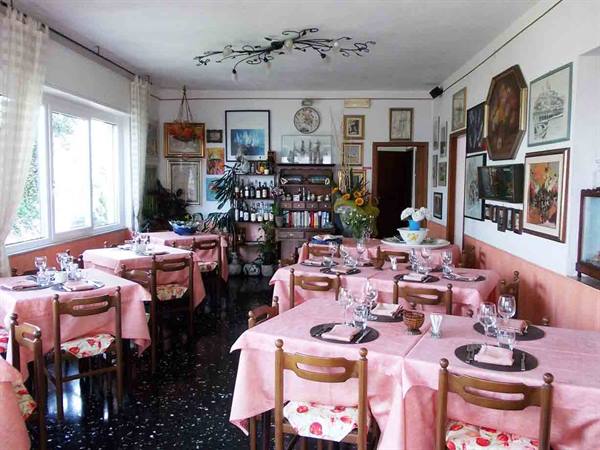 Trattoria dining room with set tables, pink tablecloths and paintings on walls