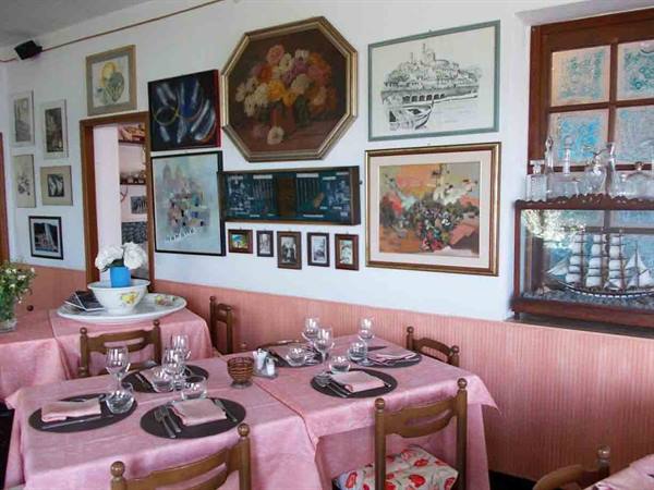 Restaurant dining room with set tables, pink tablecloths and paintings on walls